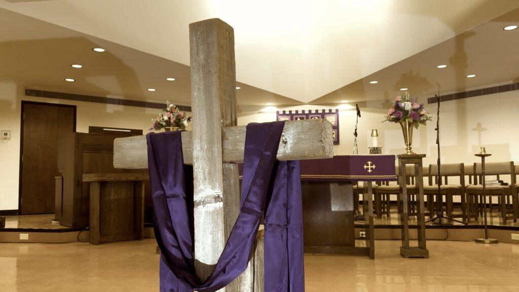 a wood cross with a purple cloth hanging over it